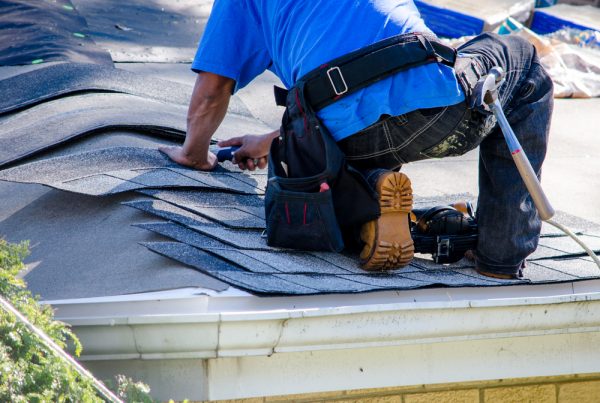 a-worker-replaces-tiles-on-the-roof-of-a-home