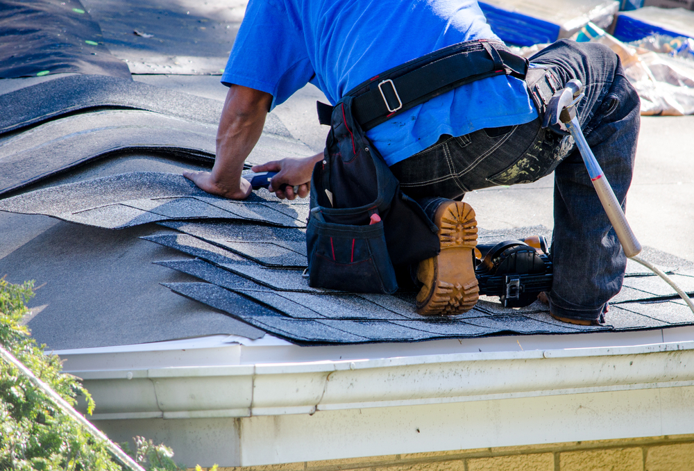 a-worker-replaces-tiles-on-the-roof-of-a-home